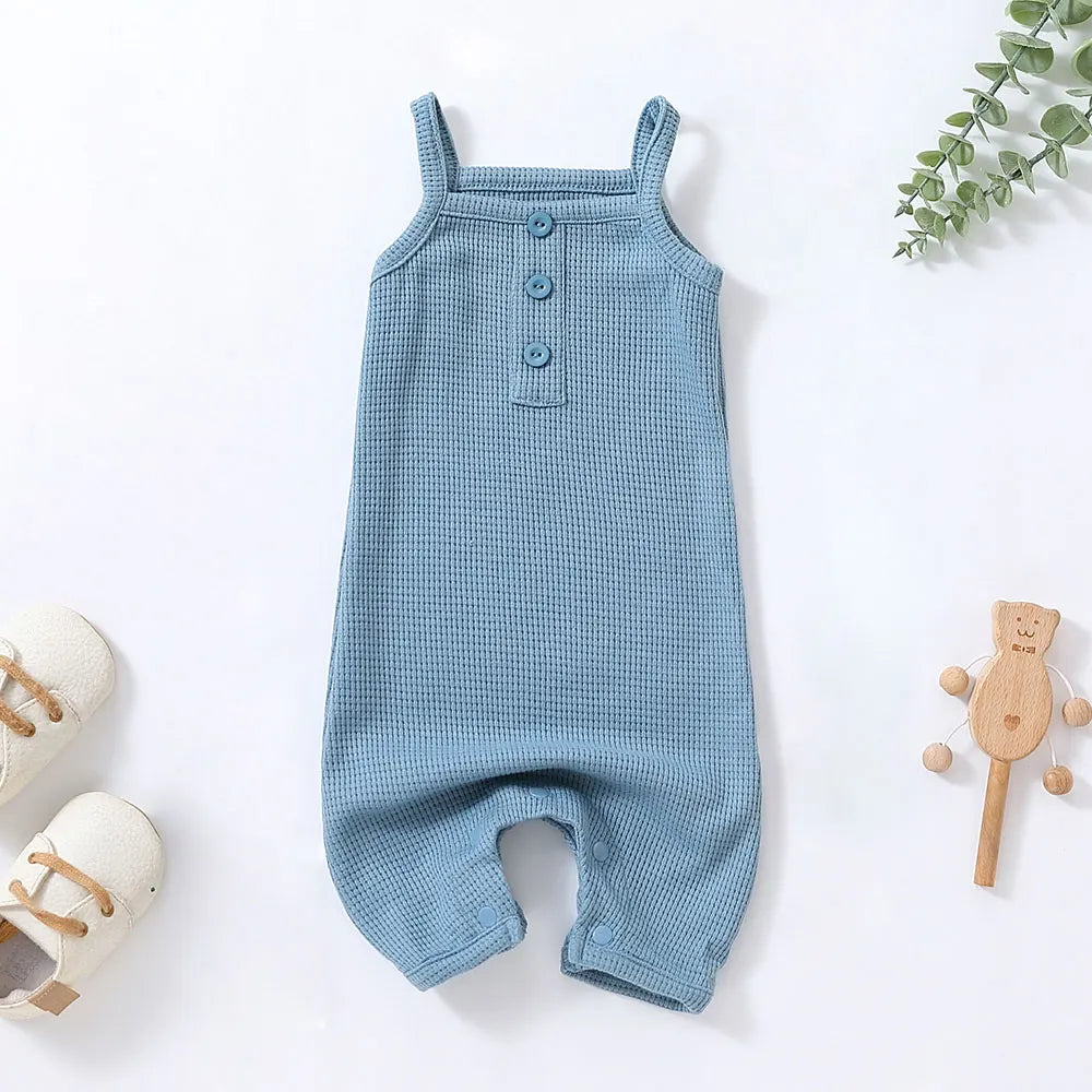Happy baby girl playing on grass in a printed sleeveless cotton romper, perfect for summer outdoor fun