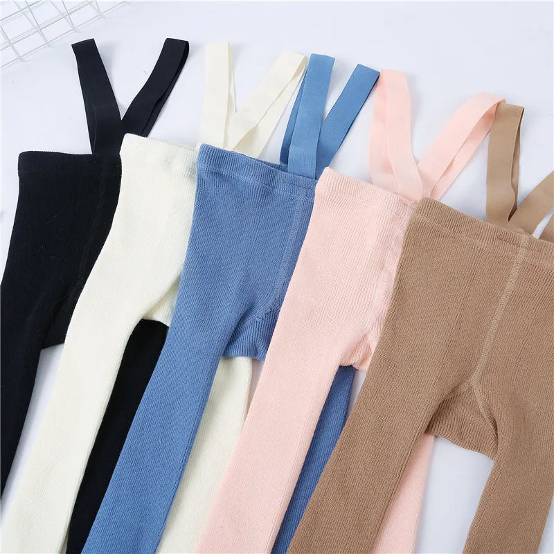 Newborn wearing comfy cream knit tights with shoulder straps, perfect for baby girl fashion.