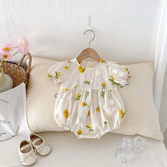 Baby girl in white floral embroidered jumpsuit, short sleeve, perfect for summer.