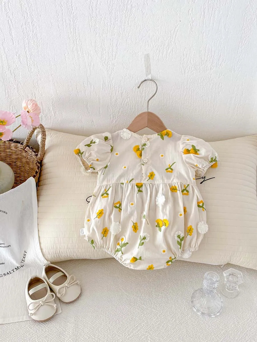 Closeup of embroidered flowers on white cotton baby girl jumpsuit summer romper.
