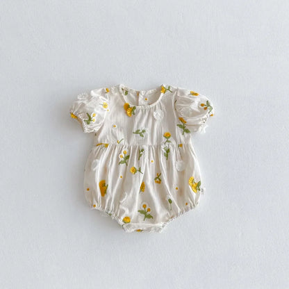 Smiling baby girl crawling in a cute embroidered floral cotton jumpsuit, ideal for summer play.