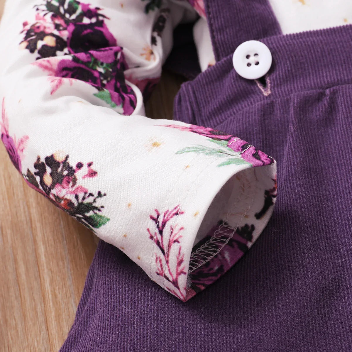 Infant girl's autumn baby wear: floral romper and solid brown suspender skirt combo.