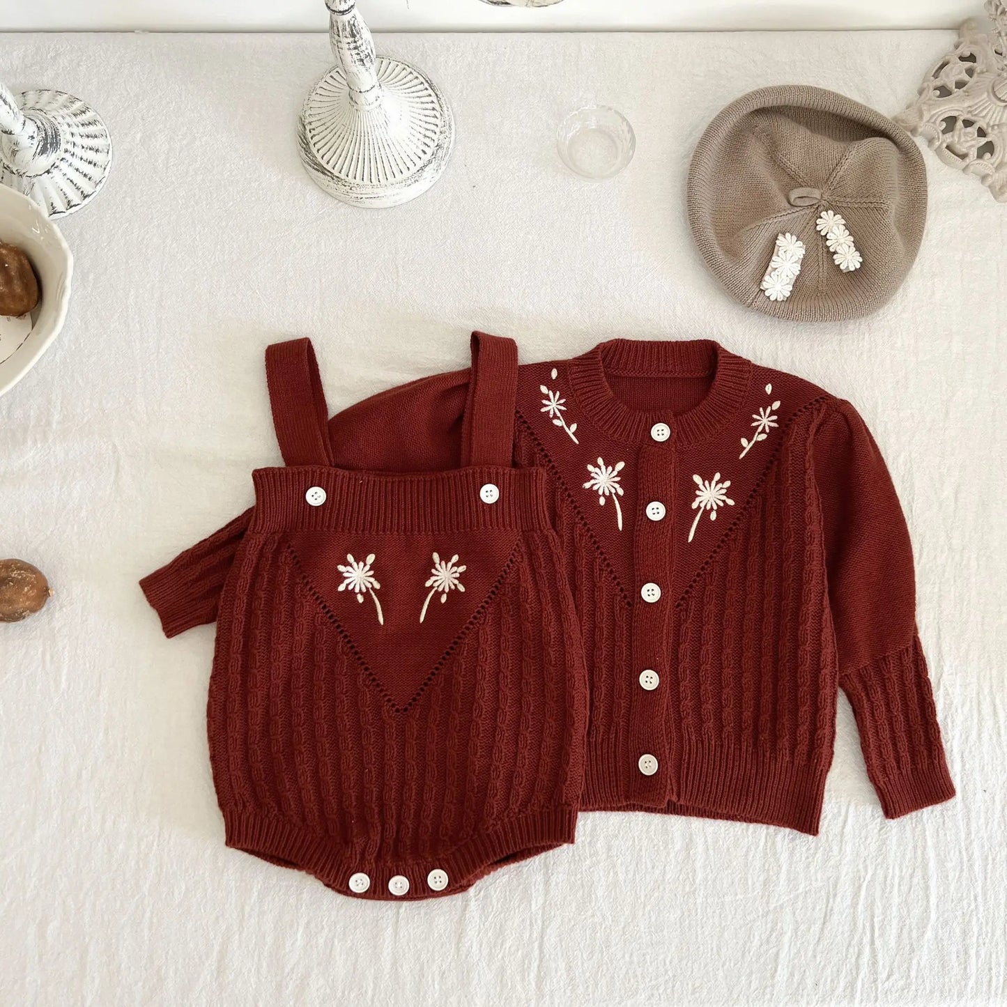 Close-up of baby girl knitted romper with intricate flower embroidery detail. Soft, cozy baby clothing.