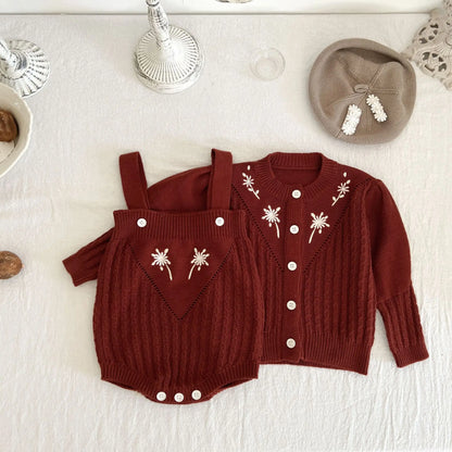 Close-up of baby girl knitted romper with intricate flower embroidery detail. Soft, cozy baby clothing.