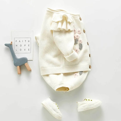Full shot of two-piece baby girl knitted set: romper & matching cardigan with lovely floral embroidery. Baby gift.