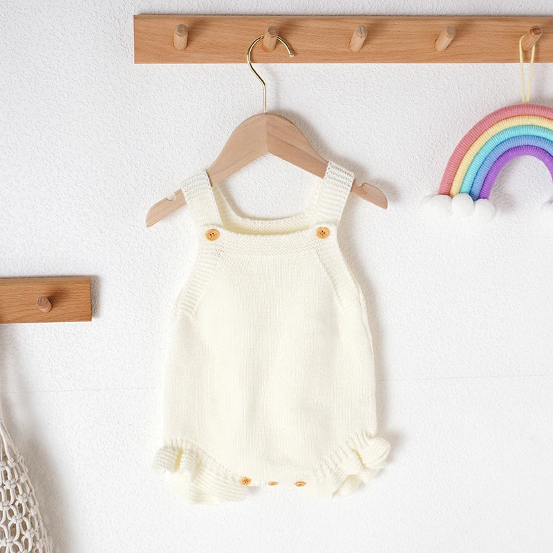 Full shot: baby girl wearing a cozy pink knitted romper, perfect summer outfit