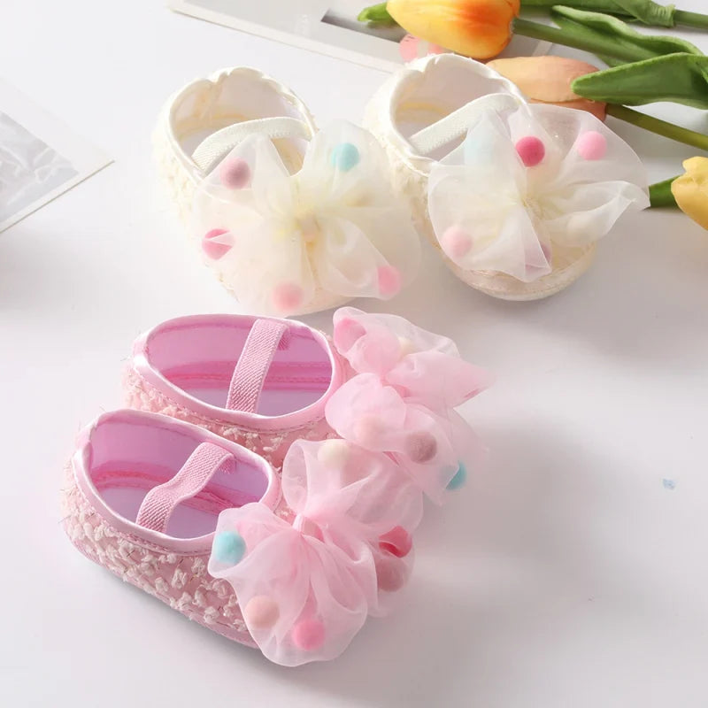 Close up of baby girl first walker shoes with delicate bow and flower embellishment
