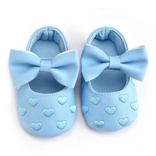 Front view of pink baby girl heart moccasins, prewalker slip-on shoes with stylish bow