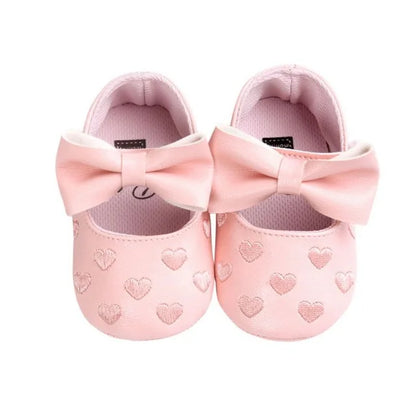 Close-up of the textured soft sole on heart print baby girl moccasins, newborn compliant
