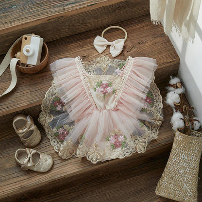 Closeup of toddler's pink princess romper with delicate floral embroidery and ruffled details.