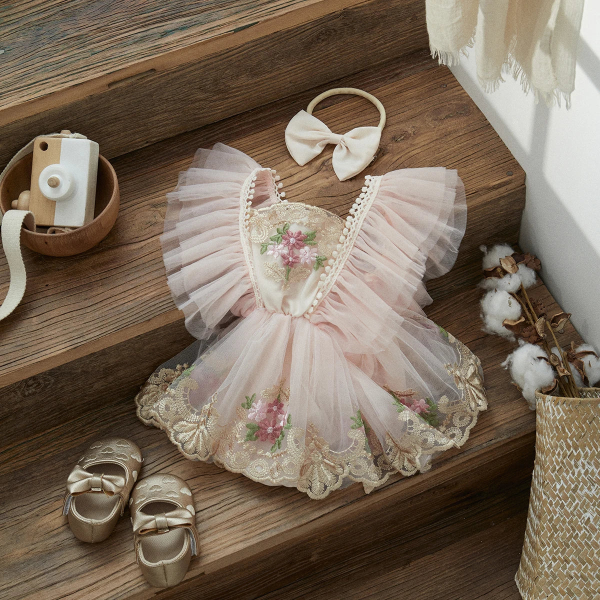 Adorable baby girl wearing a white floral embroidered princess romper and matching headband.