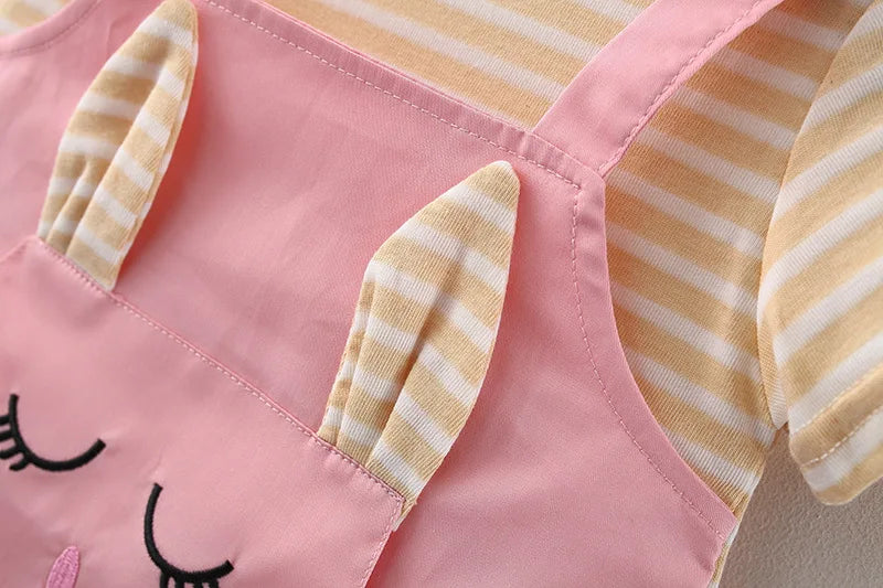 Close-up on the hem of a striped baby girl's princess dress with cartoon cat details.