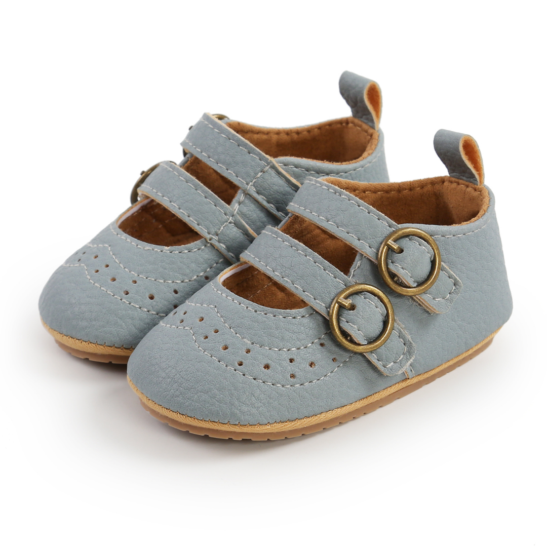 Close-up of a baby girl's first walker shoe, showing hook and loop strap and soft, flexible sole.