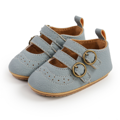 Close-up of a baby girl's first walker shoe, showing hook and loop strap and soft, flexible sole.