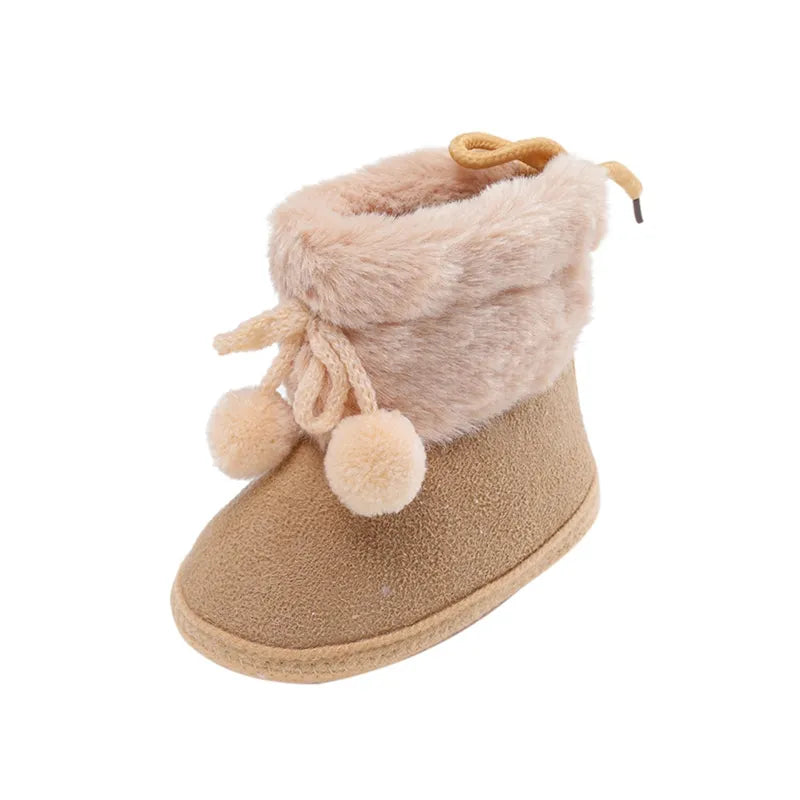 Newborn girl's pink winter booties, soft sole and adorable fluff ball design for cozy feet
