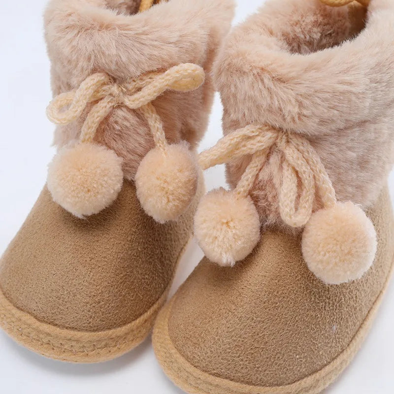 Infant girl's first walkers: pink winter snow fluff ball booties with a soft, flexible sole