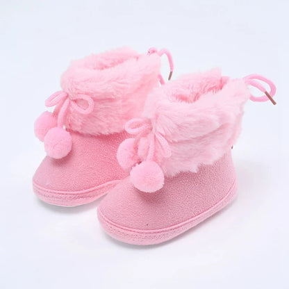 Overhead shot of pink baby girl's winter snow booties with fluff ball and soft sole