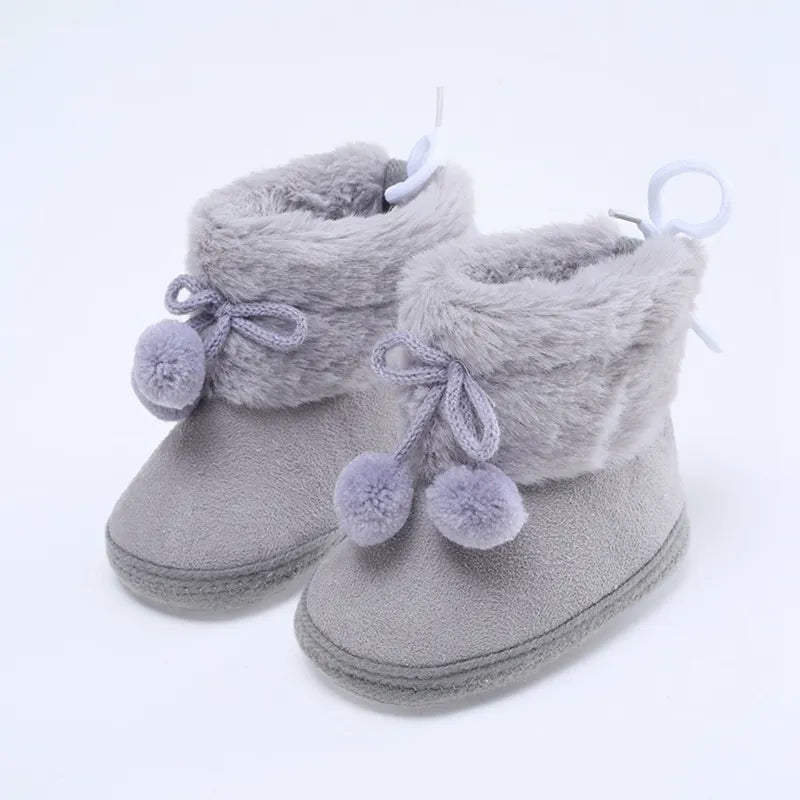 Baby girl's cozy footwear: pink winter snow booties with decorative fluff ball, soft sole