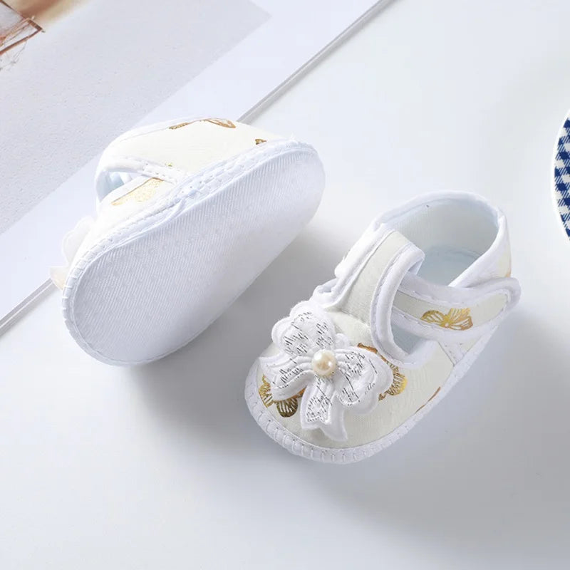 Pink floral baby girl's crib shoes with a soft sole for infants, adorned with a pretty bow, baby fashion.