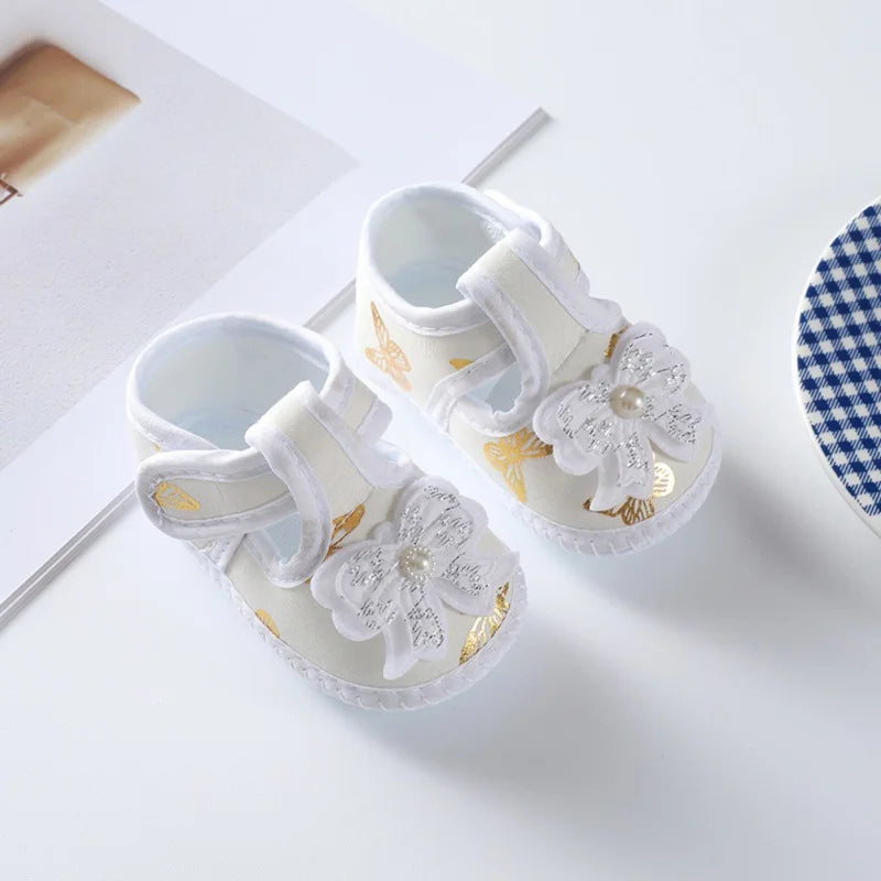 Close-up texture of baby girl's floral soft-soled crib shoes, highlighting the bow and fabric, infant comfort.
