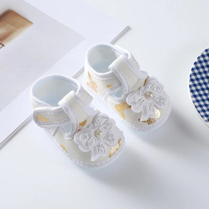 Close-up texture of baby girl's floral soft-soled crib shoes, highlighting the bow and fabric, infant comfort.