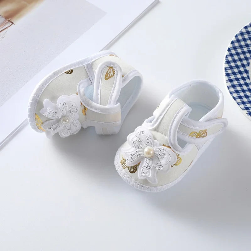 Cute pink floral baby girl crib shoes with a delicate bow, soft sole for infant comfort and early walking.