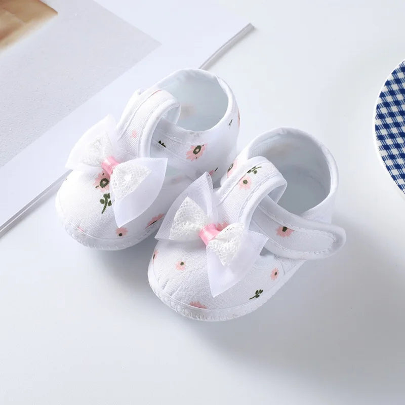 Baby girl's floral soft-soled crib shoes, showcasing all-over print and complementary pink bow for infants.