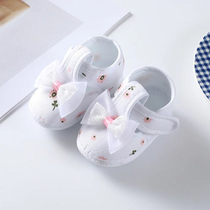Baby girl's floral soft-soled crib shoes, showcasing all-over print and complementary pink bow for infants.