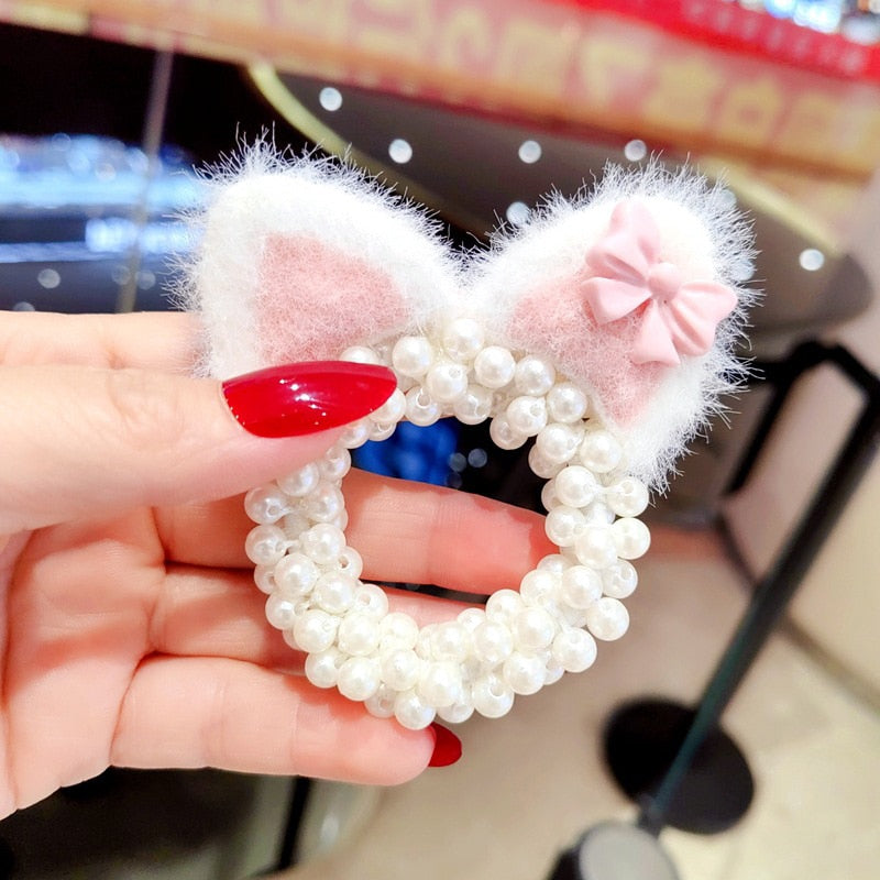 Smiling baby girl modeling a charming pearl crown hairband, ready for fashionable events