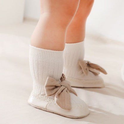 Close-up of baby girl's anti-slip cotton sock walker shoes featuring a delicate pink bowknot design