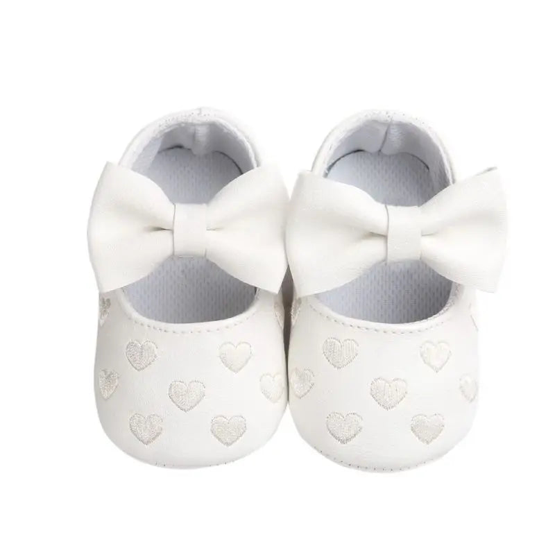 Pair of pink baby girl's non-slip toddler shoes with an adorable bow, soft and flexible sole