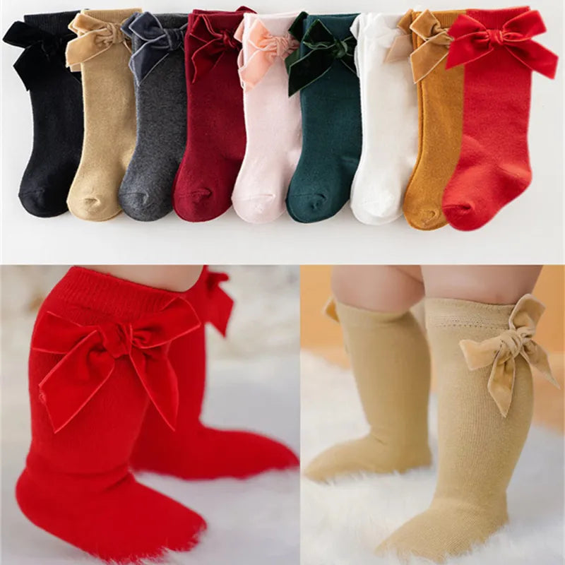 Baby girl's pink knee-high socks with large satin bow, perfect for toddler fashion.