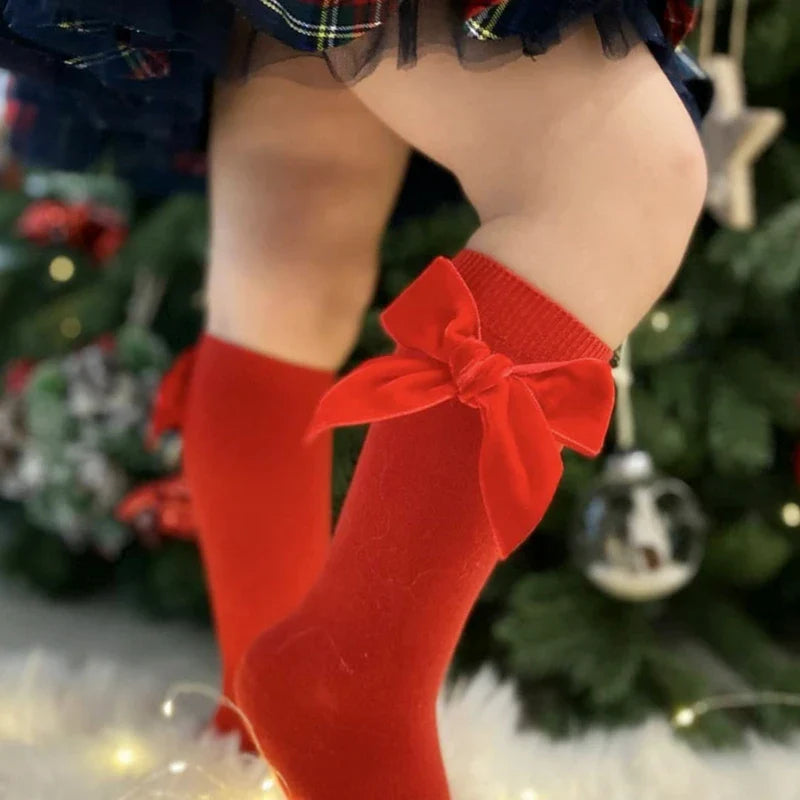 Set of 3 pairs of girls' knee-high socks, each with a different colored bow, for infants.