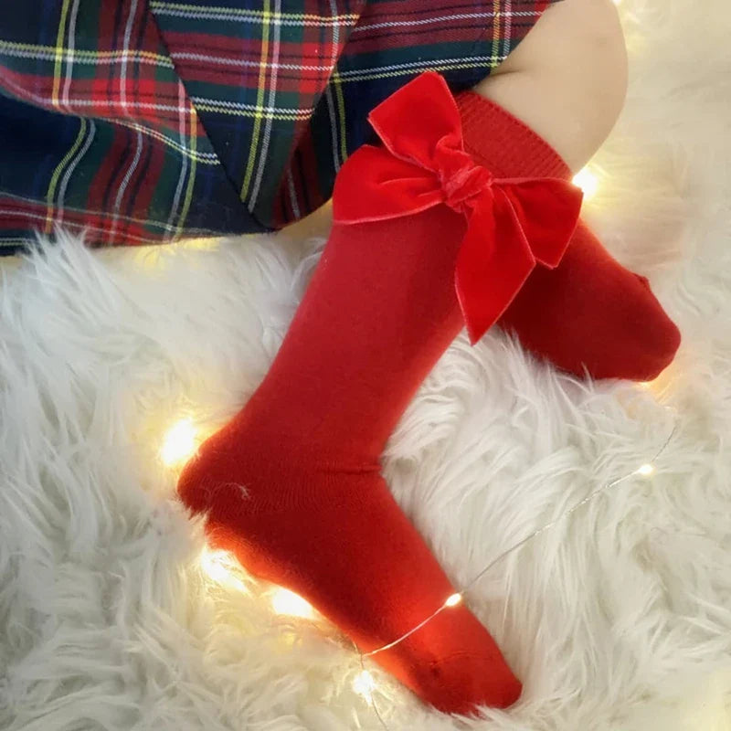 White cotton blend knee-high baby socks with an elegant white bow for infant girls.