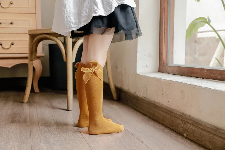 Comfortable cotton blend knee-high socks for baby girls, featuring a charming bow accent.