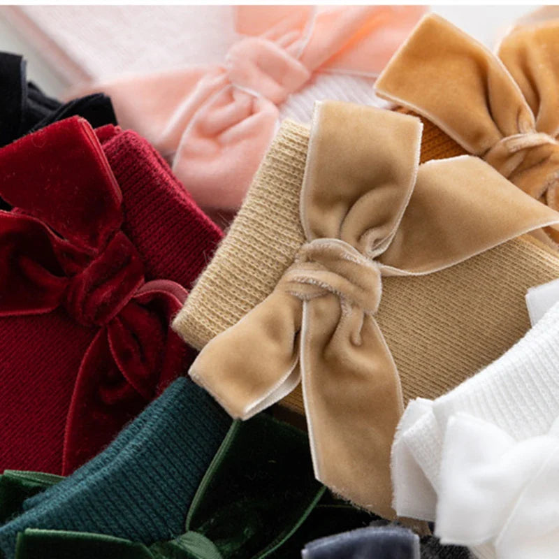 Adorable multi-pack of baby girl knee-high bow socks in assorted colors: pink, white, yellow.