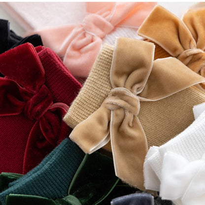 Adorable multi-pack of baby girl knee-high bow socks in assorted colors: pink, white, yellow.