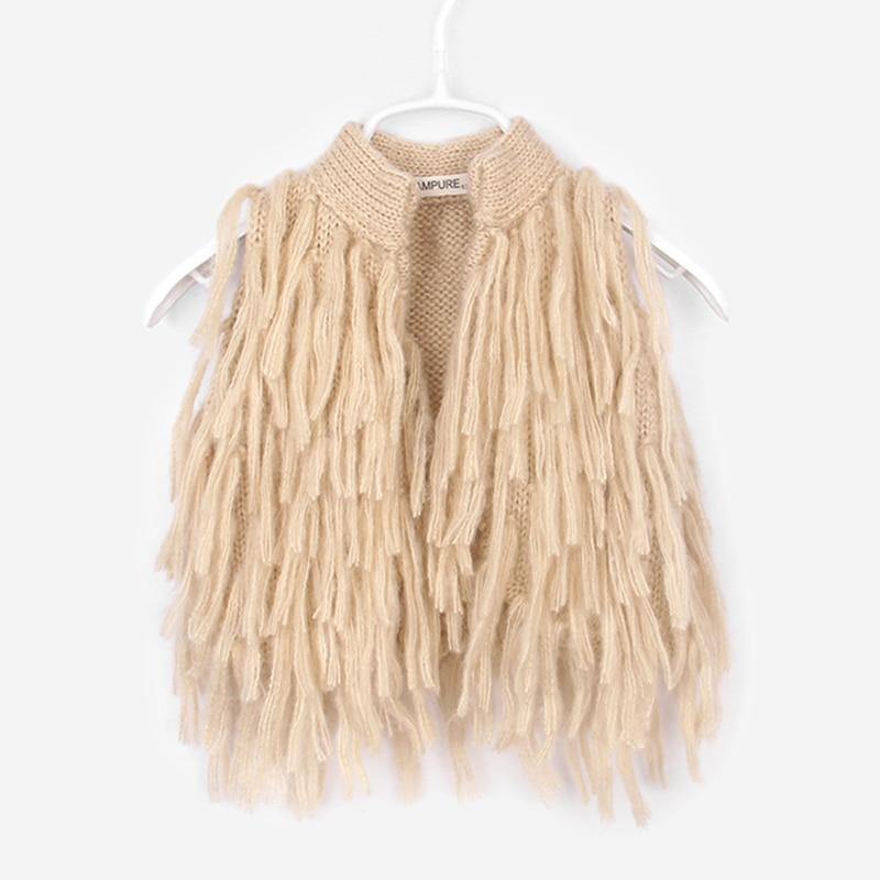 Front view of a baby girl's knitted tassel shrug, versatile sleeveless sweater for cool weather.