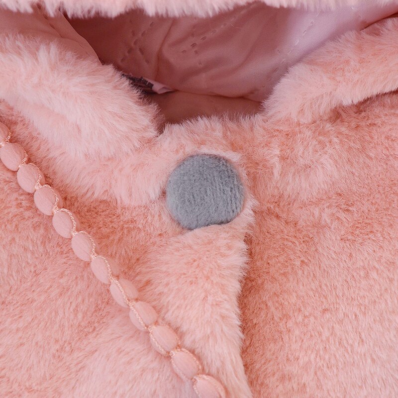 Adorable baby girl in a warm, cream-colored plush jacket with playful rabbit ears, cozy outerwear.
