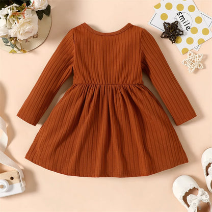 Close-up of the long sleeve cuff and ribbed texture on a baby girl's striped party dress
