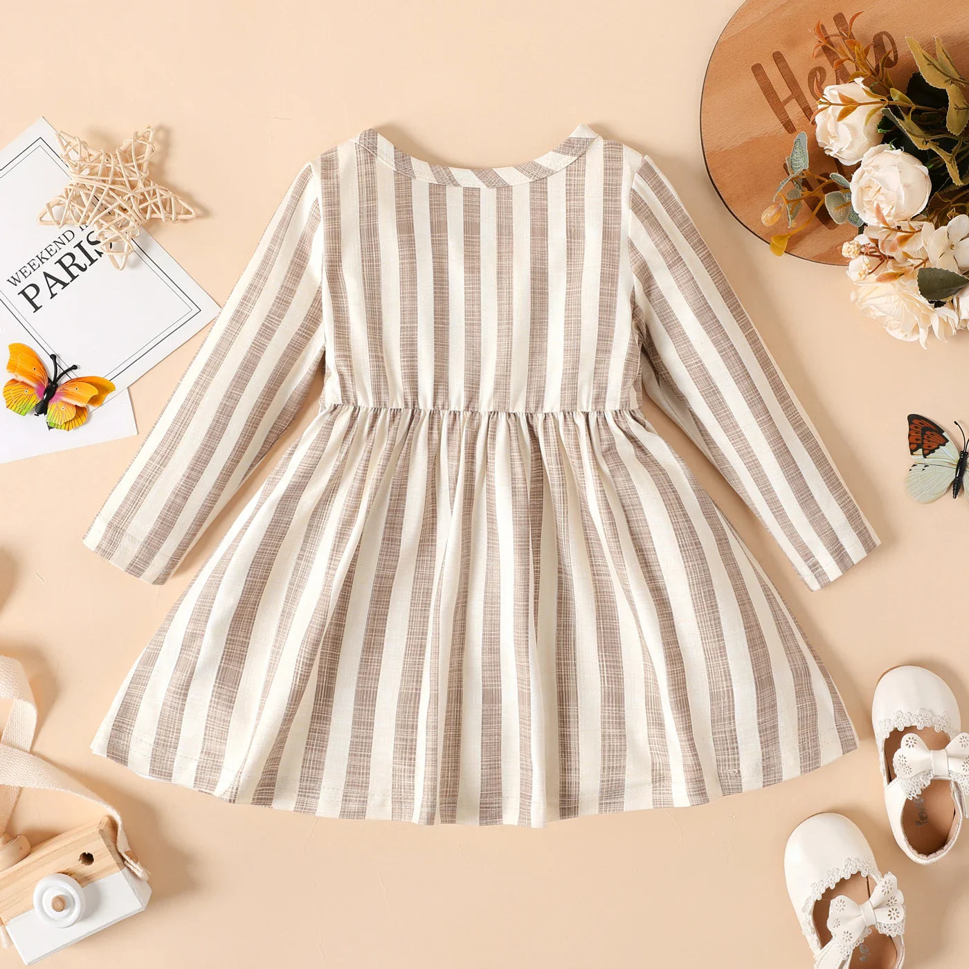 Full length image of a baby girl's long sleeve ribbed striped dress, showcasing its flowy skirt