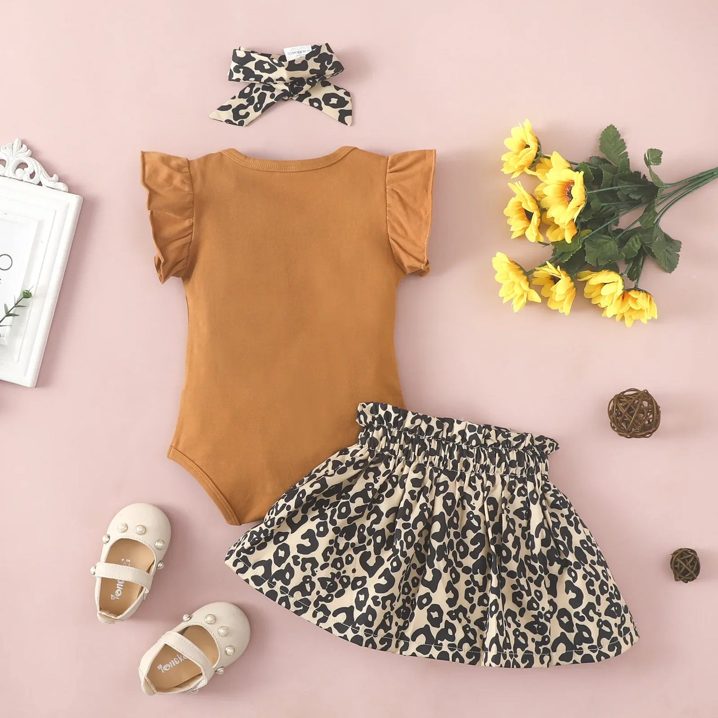 Cute baby girl in a brown ruffled sleeveless jumpsuit, perfect for summer.