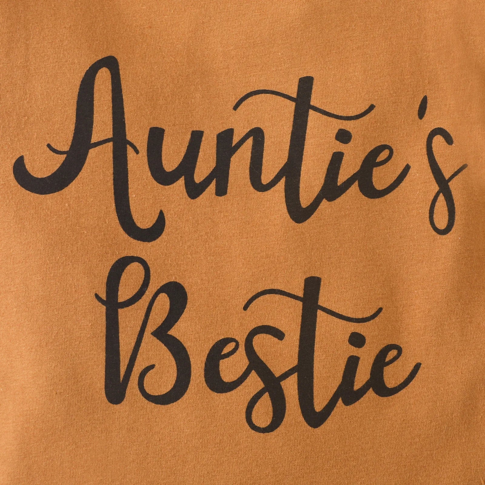Close-up of brown baby girl's sleeveless jumpsuit with delicate ruffles.