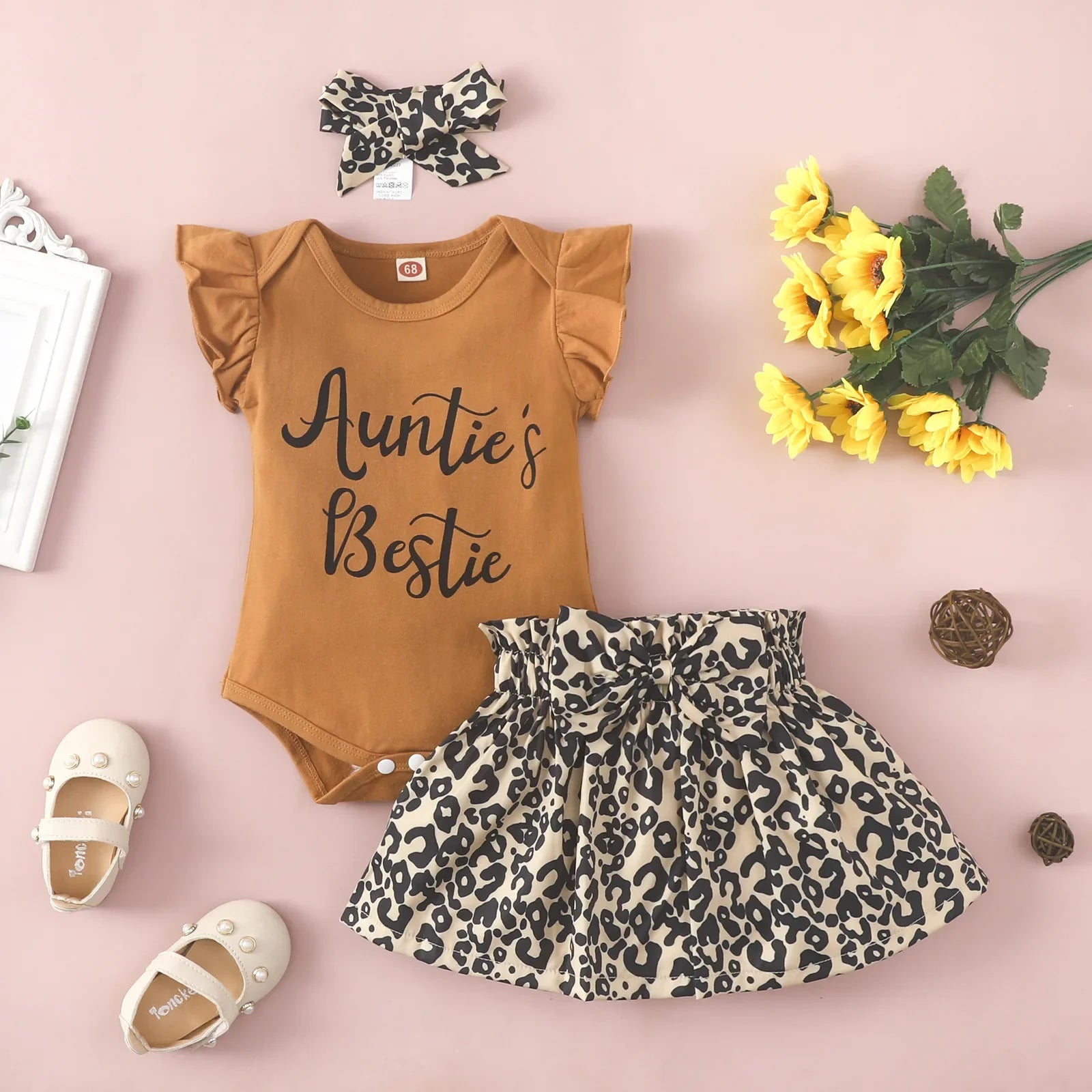Detail of the ruffled sleeveless design on a brown baby girl's jumpsuit.