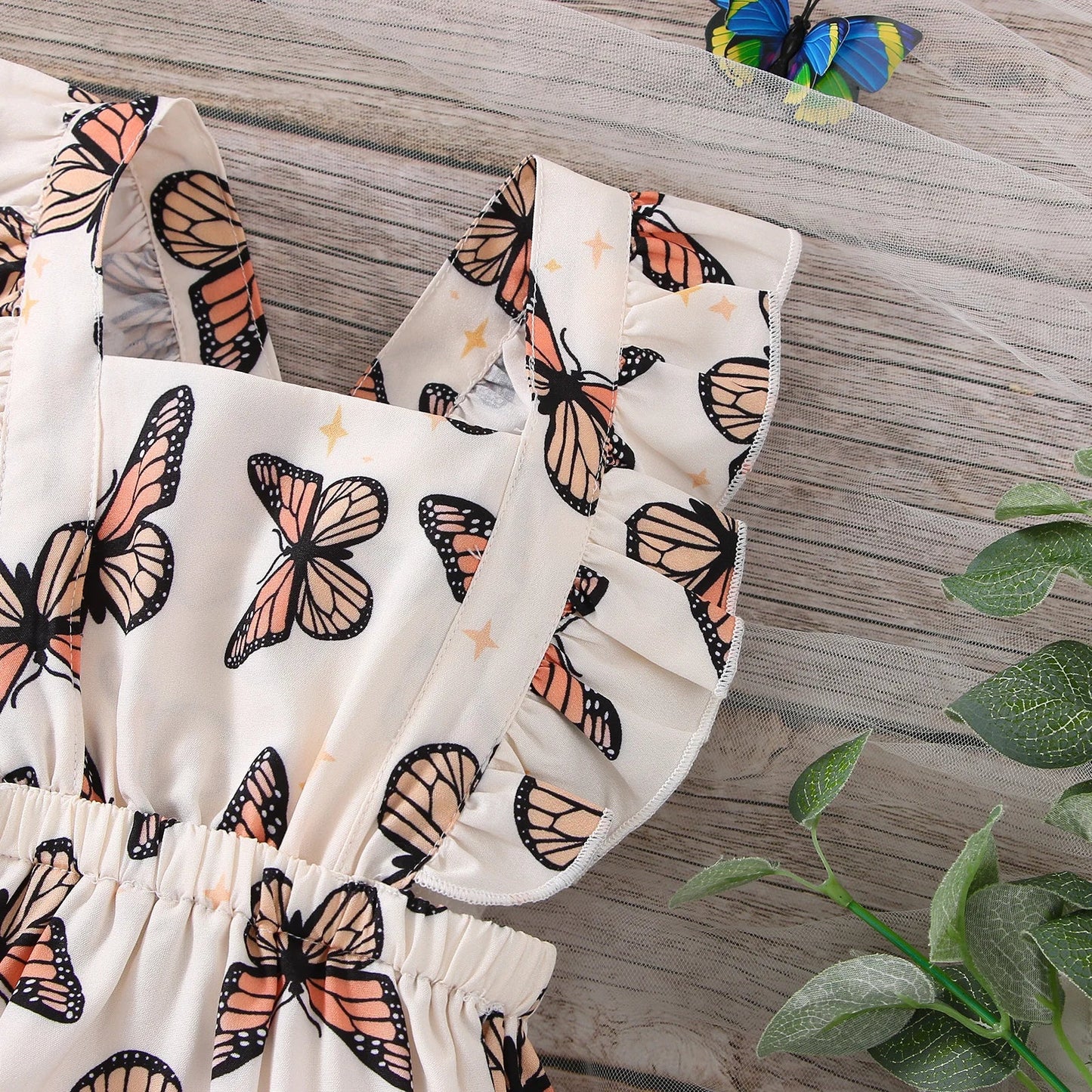 Close-up of a baby girl's bodysuit featuring vibrant butterfly print and delicate ruffle details