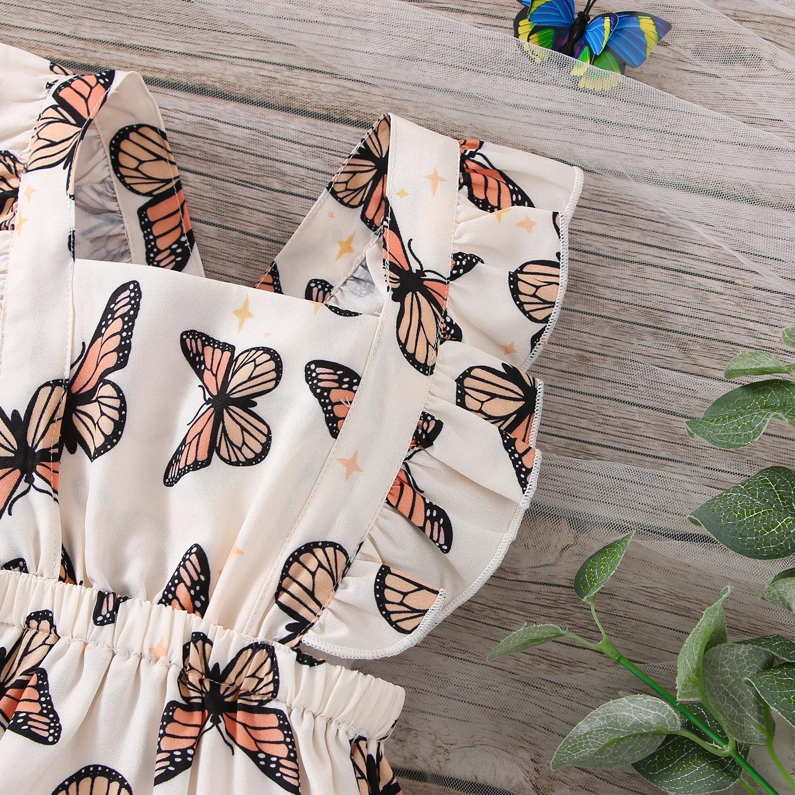 Close-up of a baby girl's bodysuit featuring vibrant butterfly print and delicate ruffle details