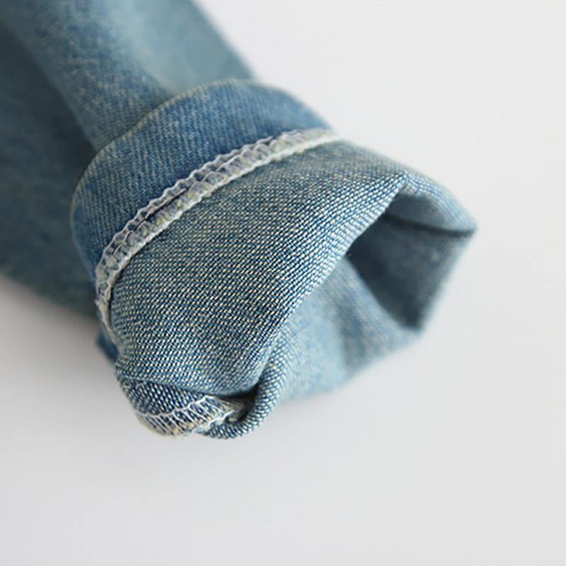 Close-up of a baby girl's soft denim romper, showing fabric detail and quality craftsmanship.