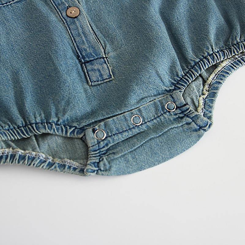 Full view of a baby girl in a stylish long sleeve denim romper jumpsuit, a cute baby outfit.