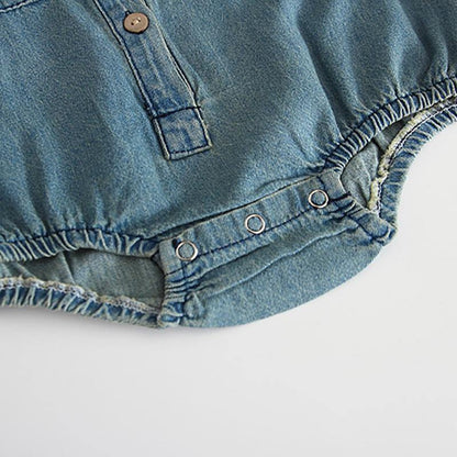 Full view of a baby girl in a stylish long sleeve denim romper jumpsuit, a cute baby outfit.
