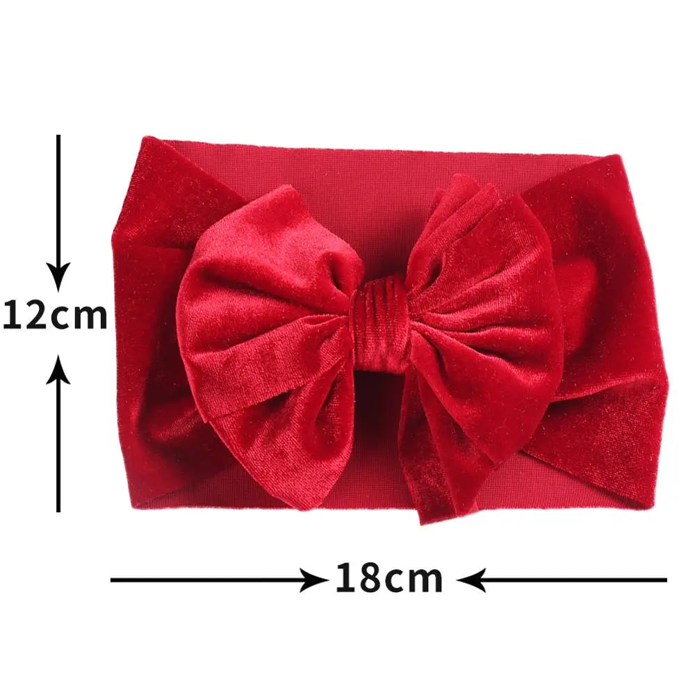 Close-up of a baby's head with a chic red velvet bow winter headband